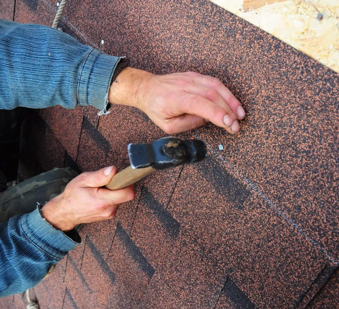 A person holding a cell phone on top of a roof.